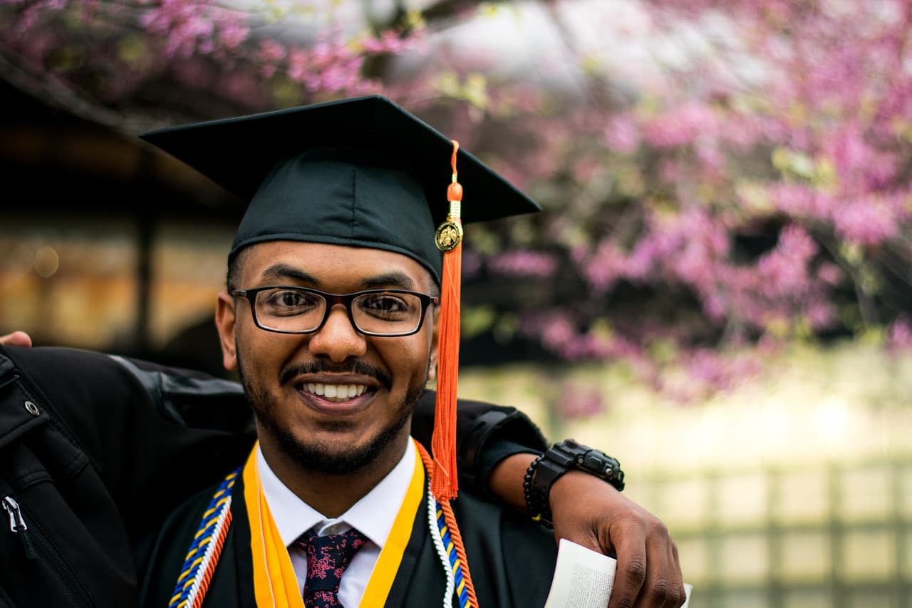 Graduate in cap and gown smiling confidently